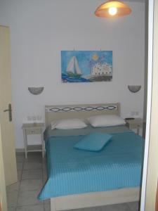 a bedroom with a blue bed with a painting on the wall at Guesthouse Irene in Afissos
