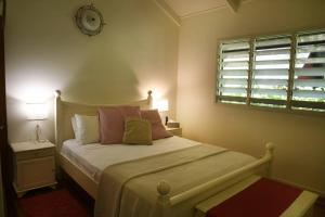 - une chambre dotée d'un lit avec une horloge murale dans l'établissement Lillypads Yellow Cottage - Rainforest Getaway, à Mission Beach