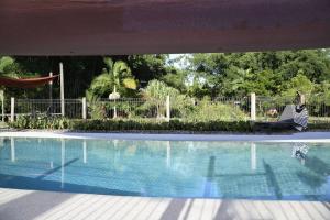 - une piscine avec un hamac à côté d'une clôture dans l'établissement Lillypads Yellow Cottage - Rainforest Getaway, à Mission Beach