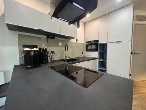 cocina con armarios blancos y encimera negra en Appartement T2 / La Défense en Courbevoie