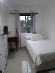 ein weißes Schlafzimmer mit einem Bett und einem Fenster in der Unterkunft Apartamento de lujo belen medellin. Piscina y gym in Medellín
