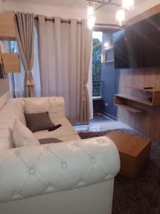 ein Wohnzimmer mit einem weißen Sofa und einem TV in der Unterkunft Apartamento de lujo belen medellin. Piscina y gym in Medellín