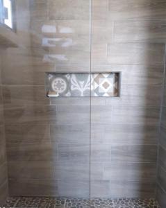a bathroom with a shower with a tile wall at Tres Velas Surf in Celestino Gasca