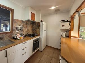 a kitchen with white cabinets and a white refrigerator at River Heads Appartment in River Heads