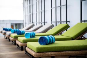 una fila di sedie verdi con cuscini blu sopra di RV Hotel Gianyar a Gianyar