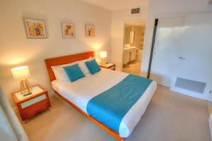 a bedroom with a large bed with blue pillows at Pavillions on 1770 in Agnes Water