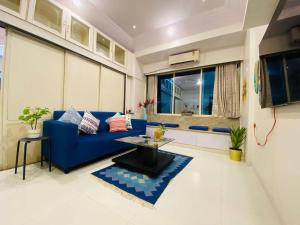 a living room with a blue couch and a table at Arora Bhavan 1BHK-1B, Khar West by Connekt Homes in Mumbai