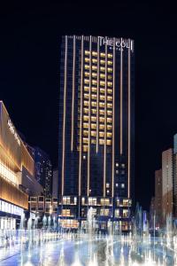 een hoog gebouw met een fontein ervoor bij The COLI Hotel Jinan in Jinan