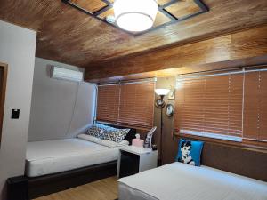 a small bedroom with two beds and a window at Leehakjang guesthouse in Mokpo