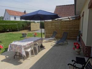 un patio con mesa y sombrilla en La belmarienne (à 5 min de Montreuil sur Mer), en Beaumerie-Saint-Martin