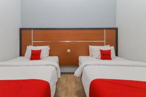 two beds with red pillows in a room at RedDoorz Plus At Swun Stay Raya Langsep in Malang