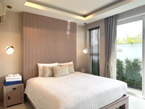 Un dormitorio con una cama grande y una ventana en Palm Oasis Pool Villa by Pattaya Holiday, en Jomtien Beach