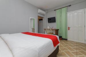 a bedroom with a large white bed with a red blanket at RedDoorz Plus At Swun Stay Raya Langsep in Malang