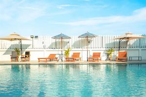 a group of chairs and umbrellas next to a swimming pool at Blue Sky Residence Airport in Ban Bang Phli Yai