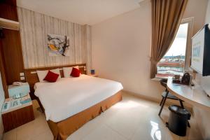 Cette chambre comprend un lit, un bureau et une fenêtre. dans l'établissement Zoom Hotel Mulawarman, à Samarinda
