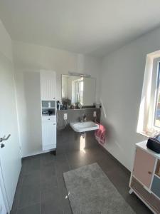 ein weißes Badezimmer mit einem Waschbecken und einem Spiegel in der Unterkunft Wunderbare Ferienwohnung mit Nähe zum Badesee in Goldenstedt