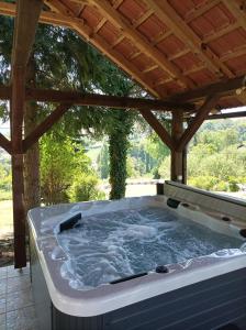 a hot tub on a patio with a wooden roof at Apartments Strmac in Slunj