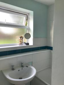 a bathroom with a sink and a mirror and a window at Betty's Cottage - Traditional Norfolk Farm Cottage in Swafield