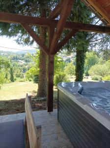 a hot tub under a wooden pergola with a bench at Apartments Strmac in Slunj
