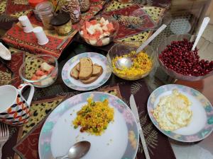 Delhi Bed and Breakfast في نيودلهي: طاولة مع أطباق من الطعام وأوعية من الفواكه