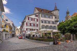 a street with buildings with tables and umbrellas at Mama Home Apartment W26 in St. Gallen