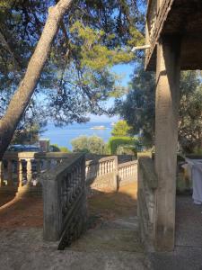 a stone bench sitting under a tree next to a fence at Apartman Novica in Herceg-Novi