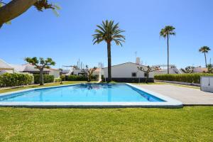 a large swimming pool in a yard with palm trees at FaroVela Suites Pasito Blanco in Pasito Blanco
