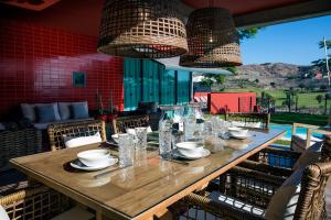 a long wooden table with glasses and plates on it at Salobre Golf Villas Premium in Salobre