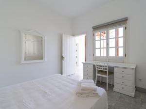 a white bedroom with a bed and a desk at Pasito Villas in Pasito Blanco