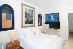 a bedroom with a white bed and a tv at Meloneras Suites in Meloneras