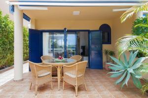 un patio con mesa, sillas y puertas azules en Meloneras Suites, en Meloneras
