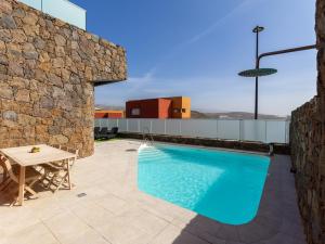 una piscina con una mesa y una pared de piedra en Salobre Villas Green, en Salobre