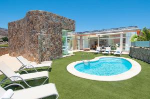 einen Garten mit Pool und Stühlen und ein Haus in der Unterkunft Tauro Villas Deluxe in La Playa de Tauro
