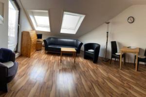 - un salon avec un canapé noir et des chaises dans l'établissement Appartement in Böblingen, à Böblingen