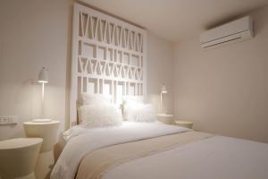 a white bedroom with a large white bed with white pillows at Agustino Beach Suites San Agustin in San Agustin