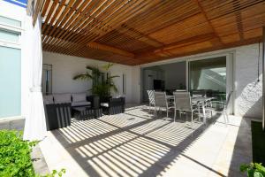 a patio with a wooden ceiling and a table and chairs at FaroVela Suites Pasito Blanco in Pasito Blanco