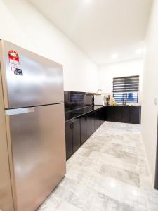 a stainless steel refrigerator in a kitchen with black counters at SORANOS HOMESTAY TAMBUN in Ipoh