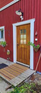 ein rotes Haus mit einer Holztür und einer Veranda in der Unterkunft BB Polle - with the horse view in Mikkeli