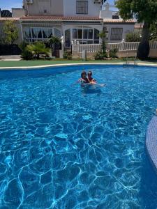 dwie osoby pływają w basenie w obiekcie Holiday home with large roof terrace near La Mata beach w mieście Torrevieja