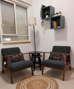 dwa krzesła i stół w pokoju z oknem w obiekcie נצר- צימר 
