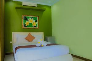 um quarto com uma cama branca e uma parede verde em Dedy Beach Inn em Kuta