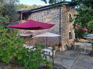 a pink umbrella and some tables and chairs and a building at podere la starza in Laureana Cilento