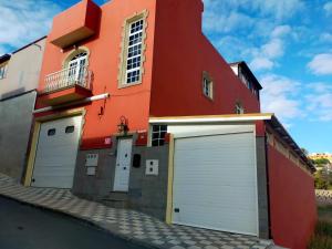 a red building with two garage doors on a street at Casa Daniella Vivienda A in Ingenio