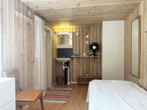 a bedroom with wooden walls and a bed and a sink at Cozy cottage on Gotland with sauna near salty baths in Lärbro