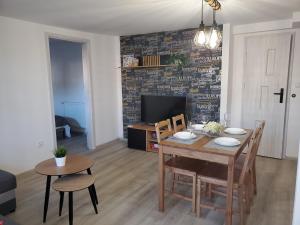 a dining room with a table and chairs and a television at Apartamenty MaK in Zator