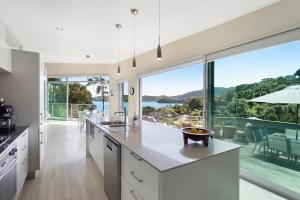a kitchen with white cabinets and a large window at Lavish Luxury - Parekura Bay Holiday Home in Rawhiti
