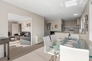 een keuken en een woonkamer met een glazen tafel en stoelen bij Seaside Sounds - Picton Upstairs Unit in Picton