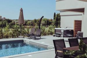 a backyard with a swimming pool and chairs and an umbrella at Villa IVaLA in Pula