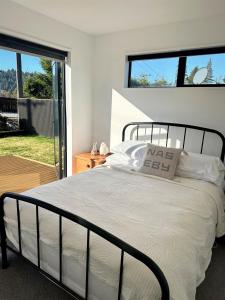 a bedroom with a bed with white sheets and windows at Naseby Modern Home in Naseby