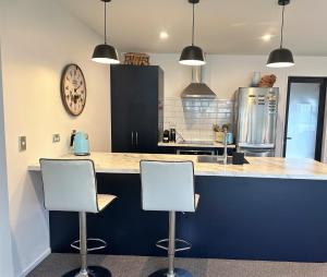 a kitchen with two white stools at a counter at Naseby Modern Home in Naseby